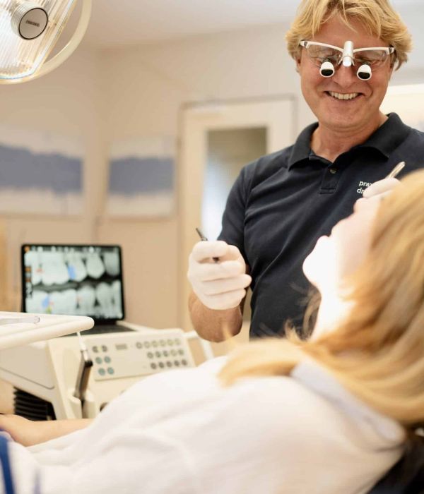 Zahnarzt Dr. Kruse lächelnd während der Behandlung mit einer Patientin